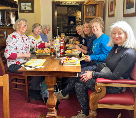 Several ladies are sat around a table eating a meal