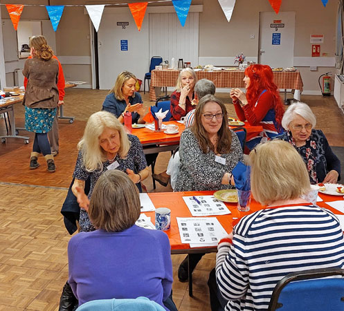 Several ladies sit around tables chatting and eating