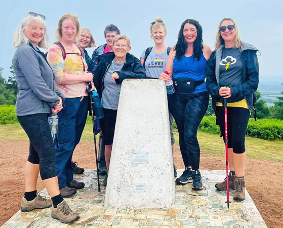 Several ladies stand around a marker stone at the top of the Wrekin