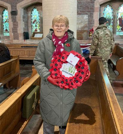 A lady holds the WI wreath to lay for Remembrance Day
