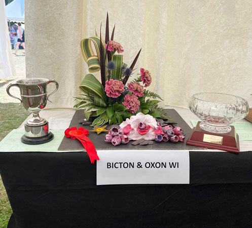 A flower arrangement and craft with a winning cup and rose bowl on each side