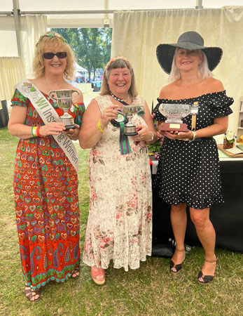 Three ladies hold trophies won at the Flower Show